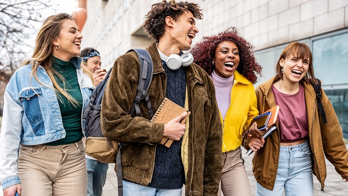 Studenten laufen lachend in einer Gruppe vor einem Gebäude