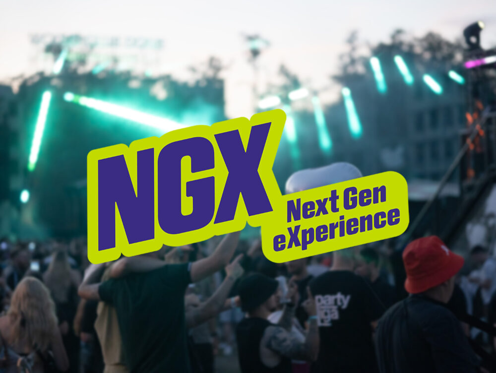 Eine Menschenmenge genießt ein Freiluftkonzert in der Abenddämmerung, während grüne Bühnenlichter in den Himmel strahlen. Der fettgedruckte Schriftzug NGX Next Gen eXperience ist deutlich über der Szene zu sehen.
